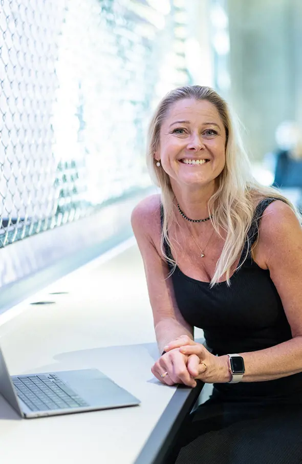 Leende medarbetare på webbyrån INKA Interactive i Malmö, sitter vid sin dator och tittar in i kameran.